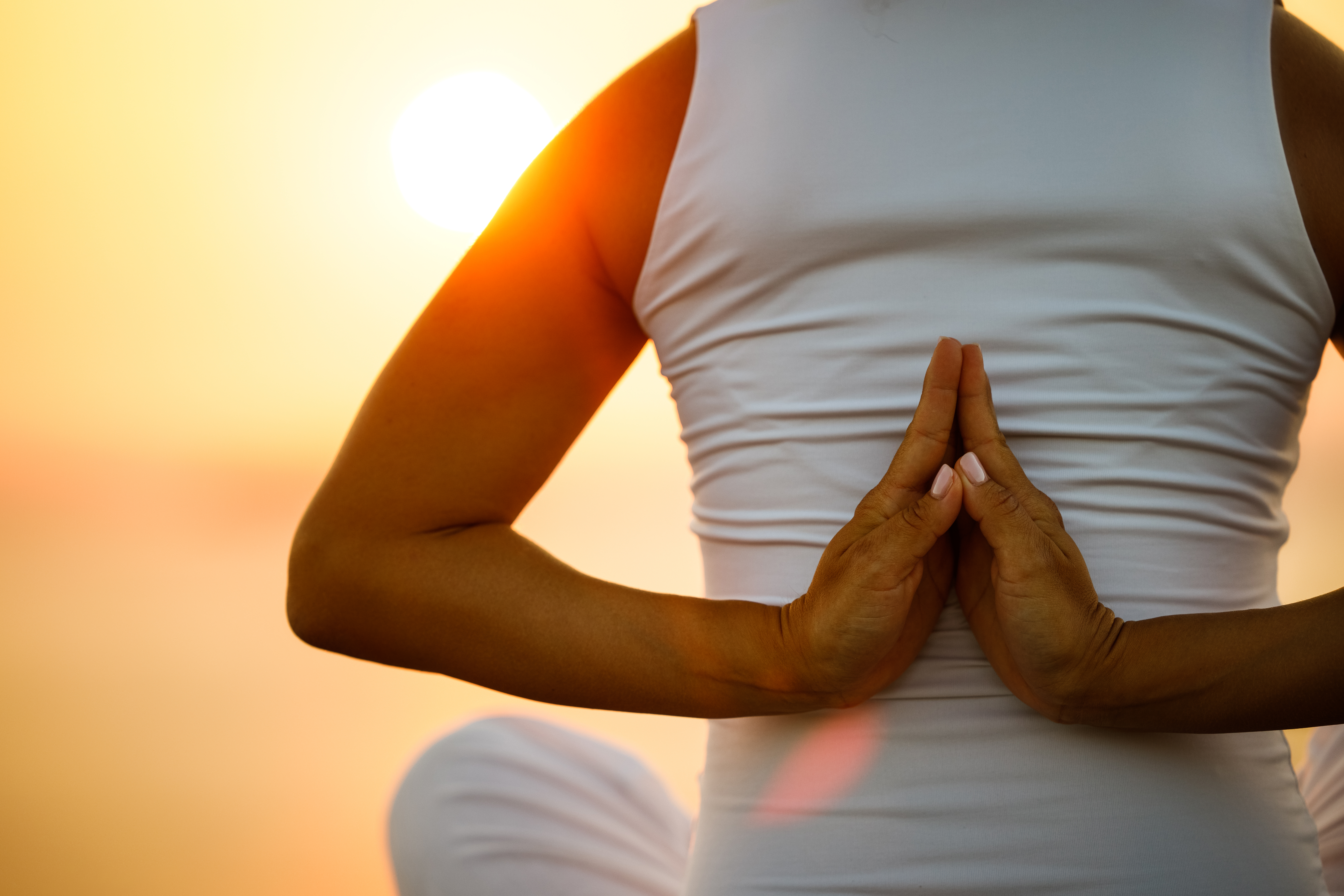 Back view of unrecognizable woman exercising Yoga with her hands clasped behind back at sunset. Copy space.
