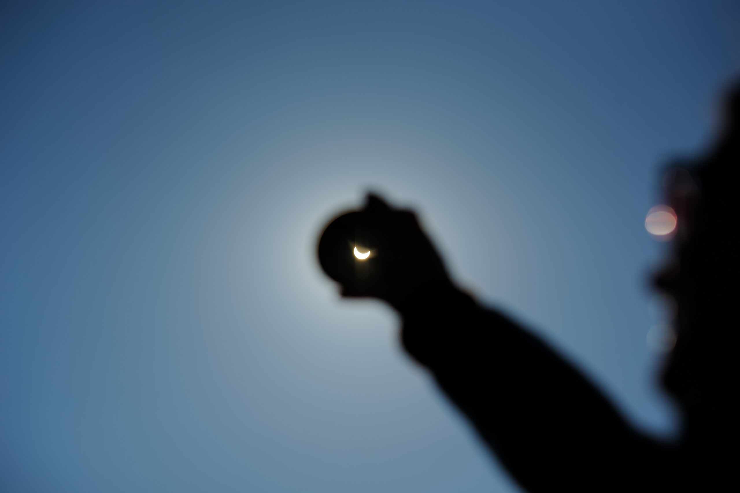 A person holding a smoked glass with solar eclipse seen through it